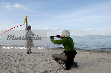 Two mature women flying a kite at Baltic Sea beach