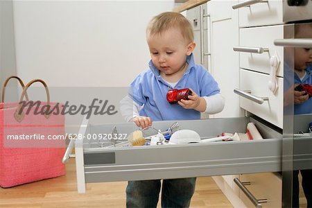 Baby boy emptying a kitchen drawer
