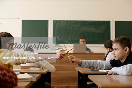 Zwei SchülerInnen kämpfen mit Stiften in einem Klassenzimmer