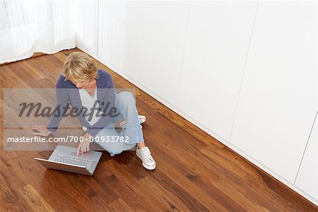 Femme assise sur le plancher, à l'aide d'ordinateur portable