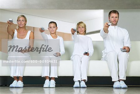 Portrait de famille assis sur le canapé, à l'aide des télécommandes