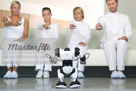 Portrait of Family Sitting on Sofa, Using Remote Controls on Robot