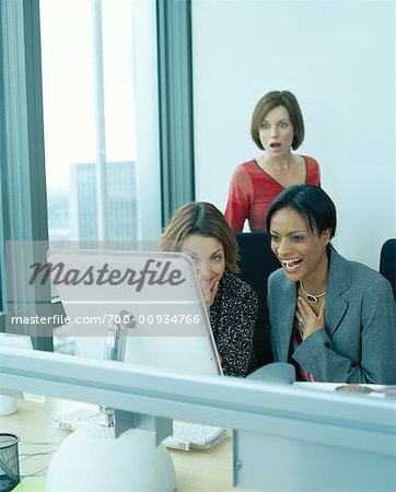Femmes rire en avant de l'ordinateur, tandis que le collègue est l'observation