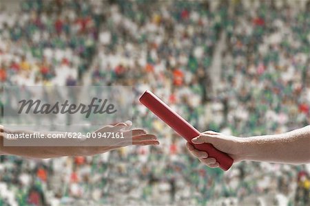 Two Runners Passing Baton In Stadium