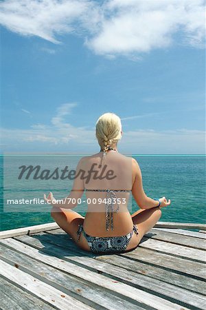 Frau sitzt auf Dock tun Yoga