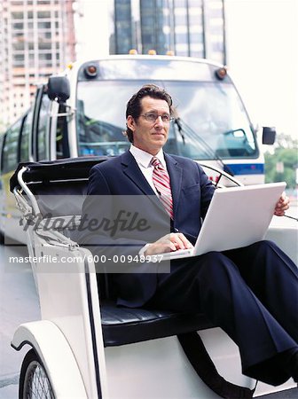 Homme d'affaires avec ordinateur portable, assis en Rickshaw