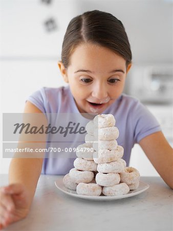 Kleines Mädchen Blick auf Haufen von Krapfen