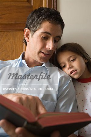 Father reading bible to daughter