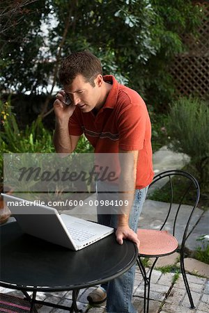 Man in Backyard using Cell Phone and Looking at Computer