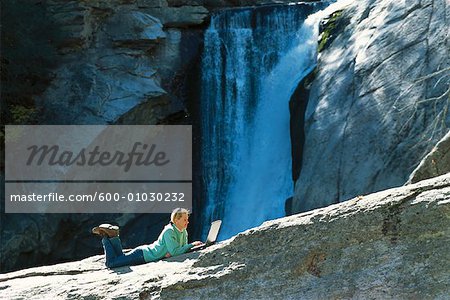 Woman Using Laptop by Waterfall