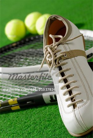 Close-up of a tennis shoe with tennis rackets and tennis balls