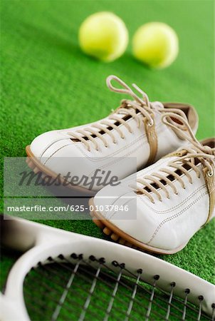 Close-up of a pair of tennis shoes with a tennis racket and tennis balls