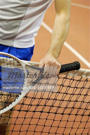 Mid section view of a man holding a tennis racket