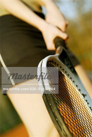 Mid section view of a woman holding a tennis racket