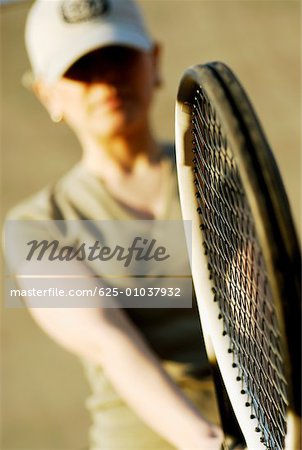 Gros plan d'une femme adulte mid tenant une raquette de tennis