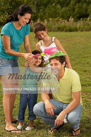 Mid adult woman and her two daughters putting butterfly nets on a mid adult man's head