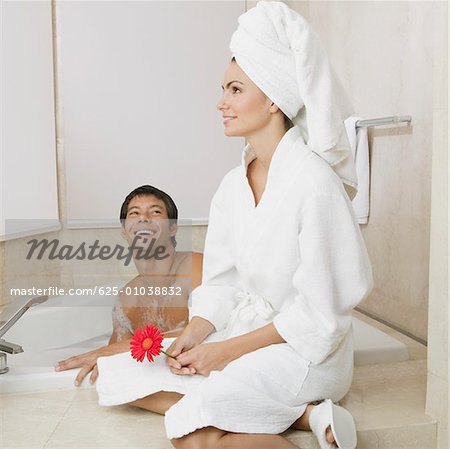 Mid adult man looking at a young woman sitting near him in the bathtub