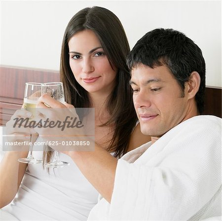 Portrait of a young woman and a mid adult man toasting with champagne flutes