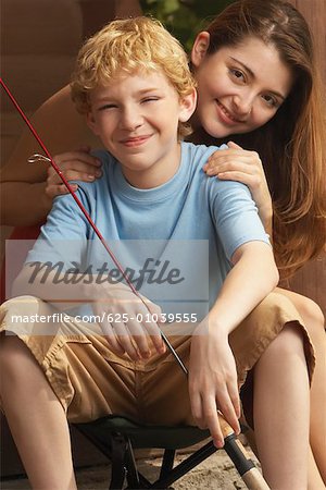 Portrait d'une fille et son frère tenant une canne à pêche