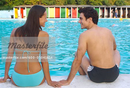 Couple à côté de la piscine, main dans la main