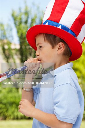 Porträt eines jungen großen Stars &amp; Stripes Hut trägt, bläst Noisemaker Horn