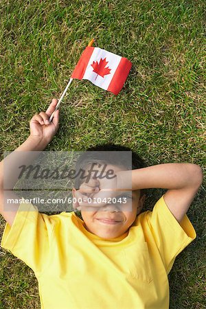 Portrait of Boy Lying on Grass, Holding Canadian Flag