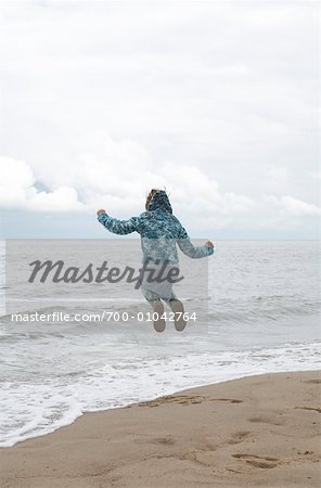 Girl Jumping in Surf on Beach