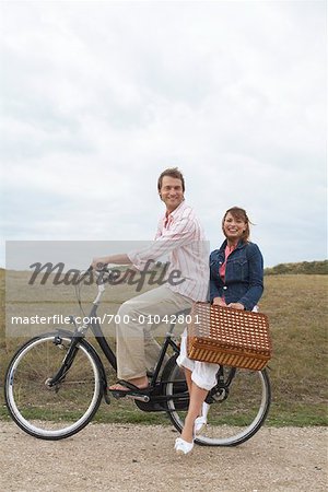 Paar mit Fahrrad und Picknickkorb befördern