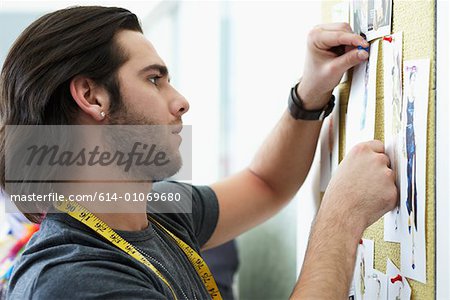 Man pinning up fashion designs