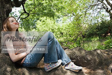 Fille assise sur un tronc d'arbre