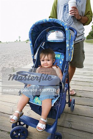 Père avec bébé dans la poussette, marchant le long de la promenade