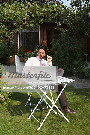Businessman With Laptop Computer and Headset in Front Yard