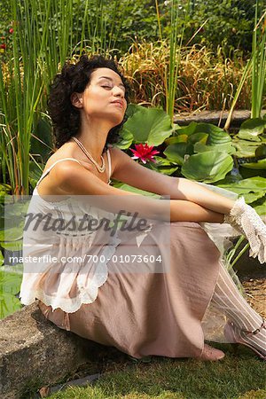 Frau sitzt am Teich