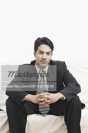 Portrait of a businessman sitting on a couch holding a mobile phone