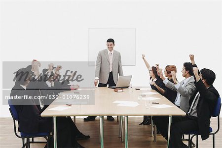 Group of business executives raising their hands at a presentation