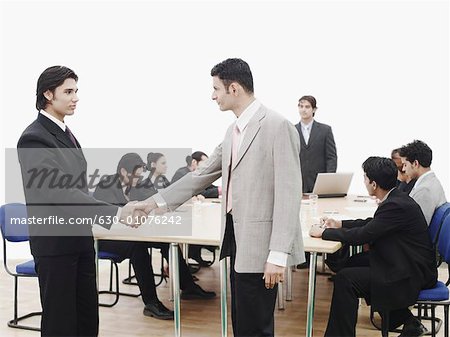 Side profile of two businessmen shaking hands in a meeting