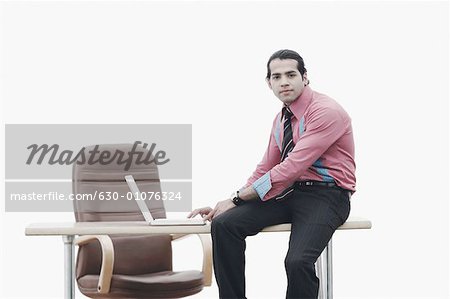 Portrait d'un homme d'affaires assis sur la table de travail sur un ordinateur portable