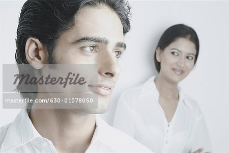 Junger Mann mit einer jungen Frau hinter ihm lächelnd