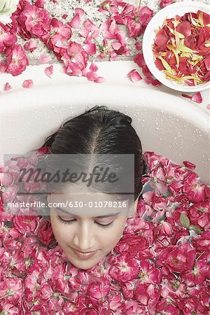 Vue grand angle d'une jeune femme se trouvant dans une baignoire recouverte de pétales de fleurs