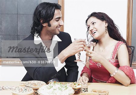 Junges Paar, Toasten mit Weinglas am Esstisch