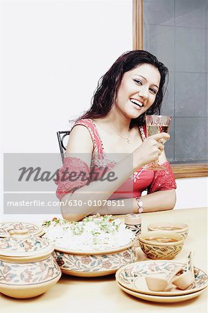 Portrait of a young woman with a wineglass in her hand sitting at the dining table