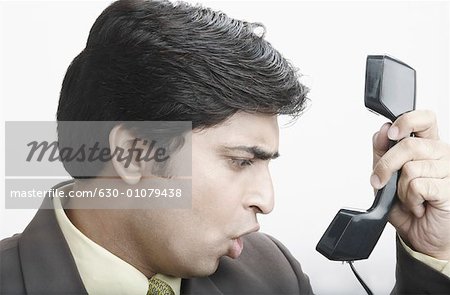 Close-up of a businessman making a face in front of a telephone receiver