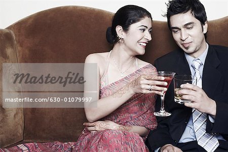 Jeune couple griller avec martini et whisky, verres