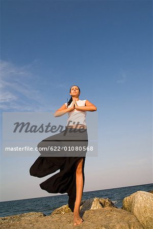Jeune femme de faire des exercices d'yoga sur le rocher