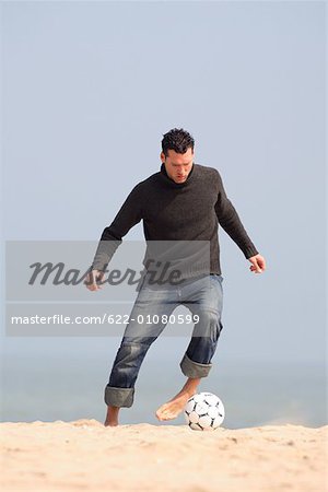 Caucasian male practicing soccer on beach