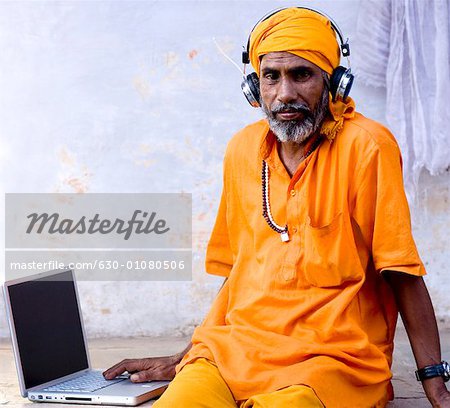 Porträt eines Reifen Mannes sitzt vor einem Laptop tragen Kopfhörer, Pushkar, Rajasthan, Indien