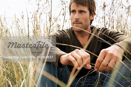 Portrait d'un homme assis dans l'herbe longue