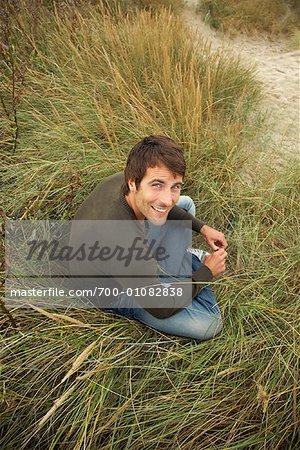 Porträt der Mann sitzt im hohen Gras