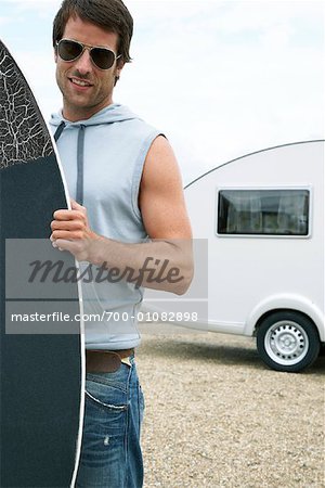 Man Holding Skimboard in Front of Trailer