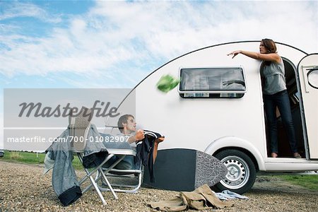 Woman Throwing Clothes at Man Sitting Outside Trailer